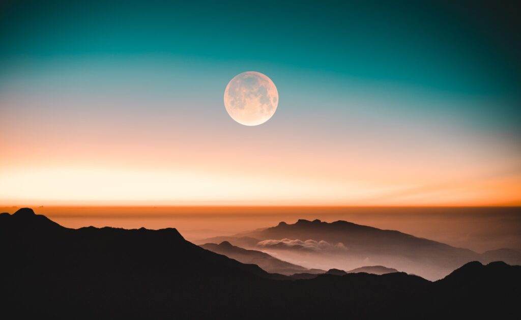 A sunrise with the moon visible in the sky